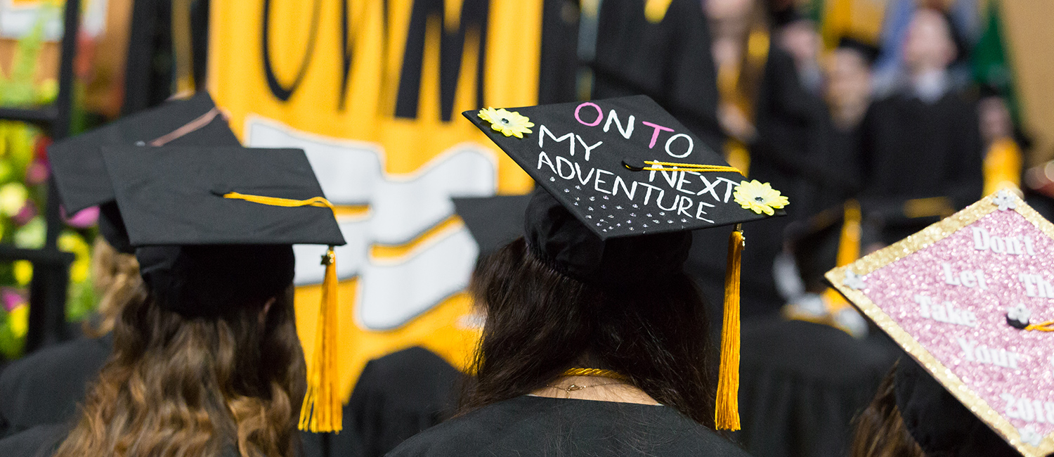 Graduation caps at commencement. One decorated cap reads, "On to my next adventure."