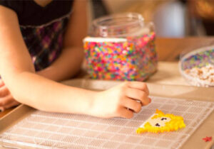 Girl arranging beads in the shape of a person's head