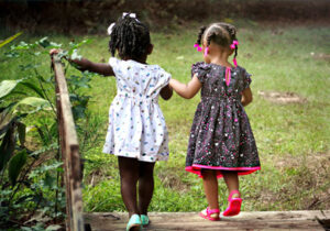 Two little girls in dresses and braids walking together