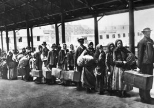 Black and white image of people standing in line with suitcases