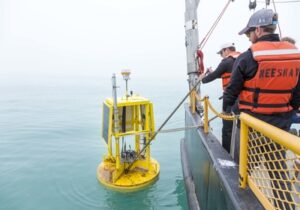 People on Neeskay research vessel deploying yellow buoy