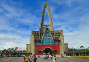 Red and blue building with tall center arch with people walking around