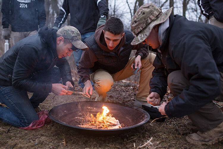 UWM students learn how to make fire during their cold-weather survival training.