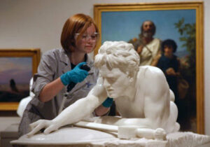 Student restoring marble statue in art museum