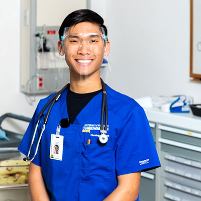 Male nursing student standing in scrubs with stethoscope around shoulders