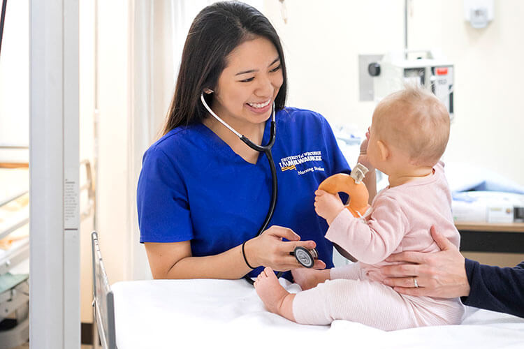 Nursing student using stethoscope with a baby