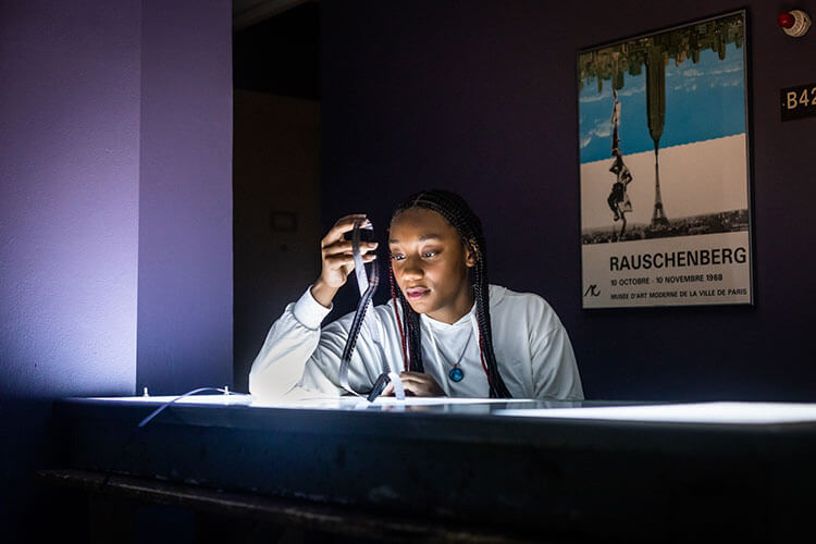 Black female film student looks at film strip