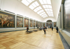 Interior of an art museum with patrons browsing large paintings