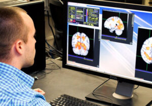 Man sitting in front of computer screen showing brain scan images