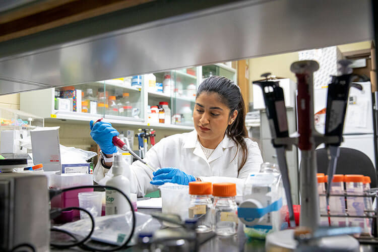 Female student wearing labcoat and holding pipette