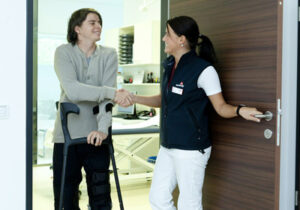 Young man using crutches shaking hand of woman