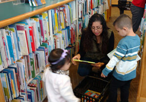 Woman and two children looking at a book in a library