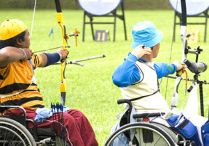 Two wheelchair users doing archery