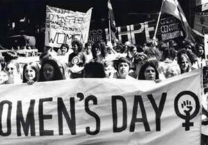 Black and white photo of college students holding Women's Day banner