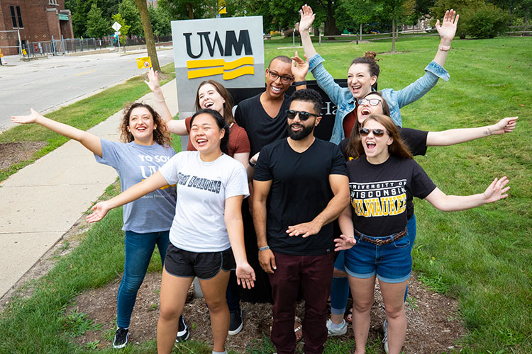 Group of UWM students posing in front of UWM sign