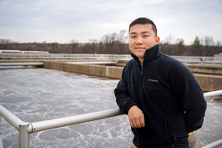 Young man standing in front of a water treatment plant