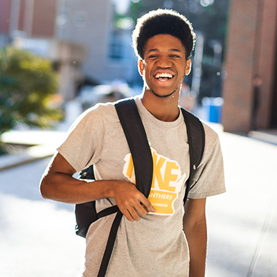 Male UWM student wearing a UWM shirt and smiling