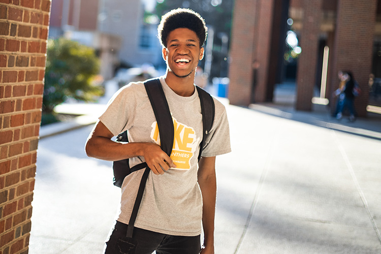 Male UWM student wearing a UWM shirt and smiling