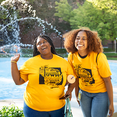 Two Black female UWM students standing and smiling in front of fountain