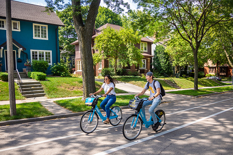 Two UWM students riding bikes through the campus neighborhood