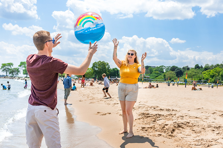 Two UWM students tossing a beach ball on the beach