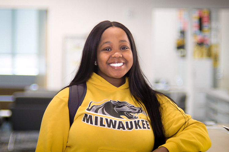 Smiling Black female UWM student wearing a yellow UWM hoodie