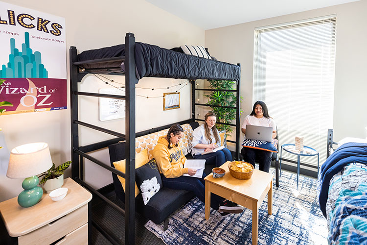 Three female UWM students sitting in dorm room and studying