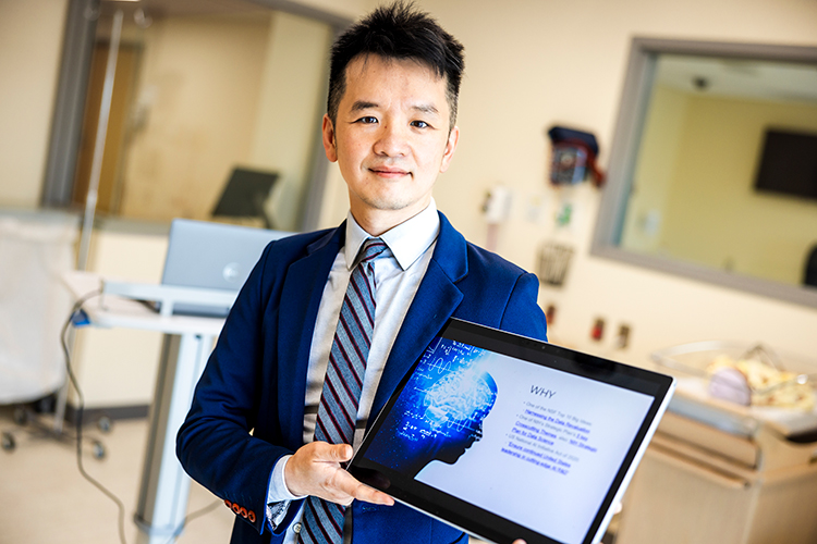 Jake Luo holding a tablet device in a medical lab