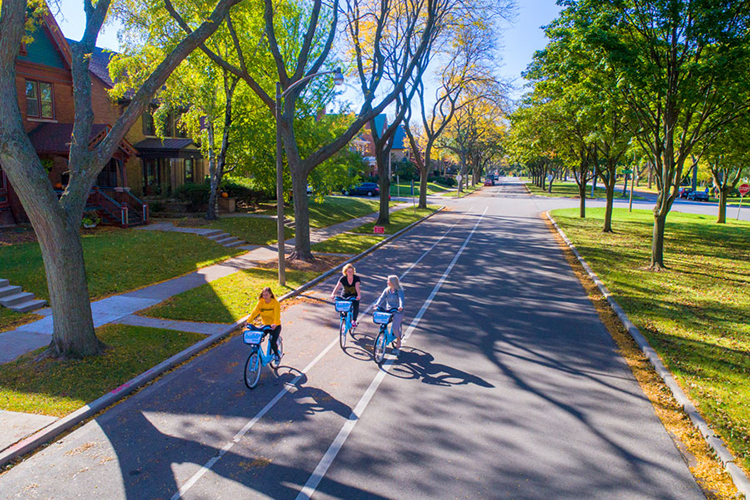 Three UWM students riding bikes in a neighborhood near campus.