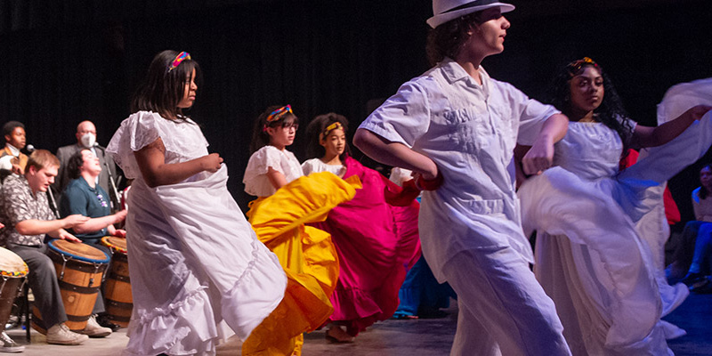 Community members and young students performing a dance during World Percussion