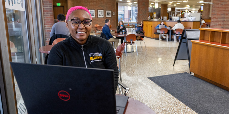 UWM student Kayla J in the library working on a laptop.