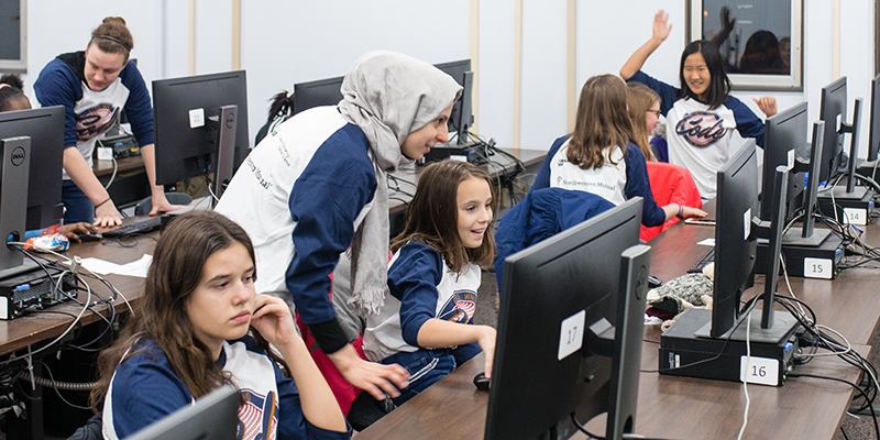 Girls working on computers with mentors at the Girls Who Code event