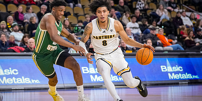 UWM Men's basketball player with the ball and running toward the basket during a game.