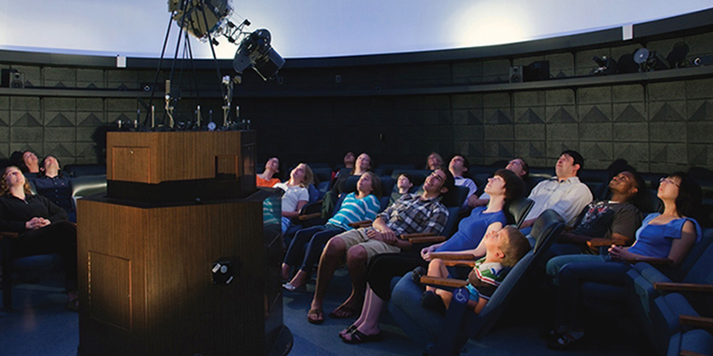 An audience looking up at the planetarium sky