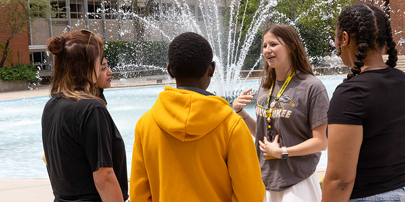 UWM campus tour guide with guests in front of the UWM fountain